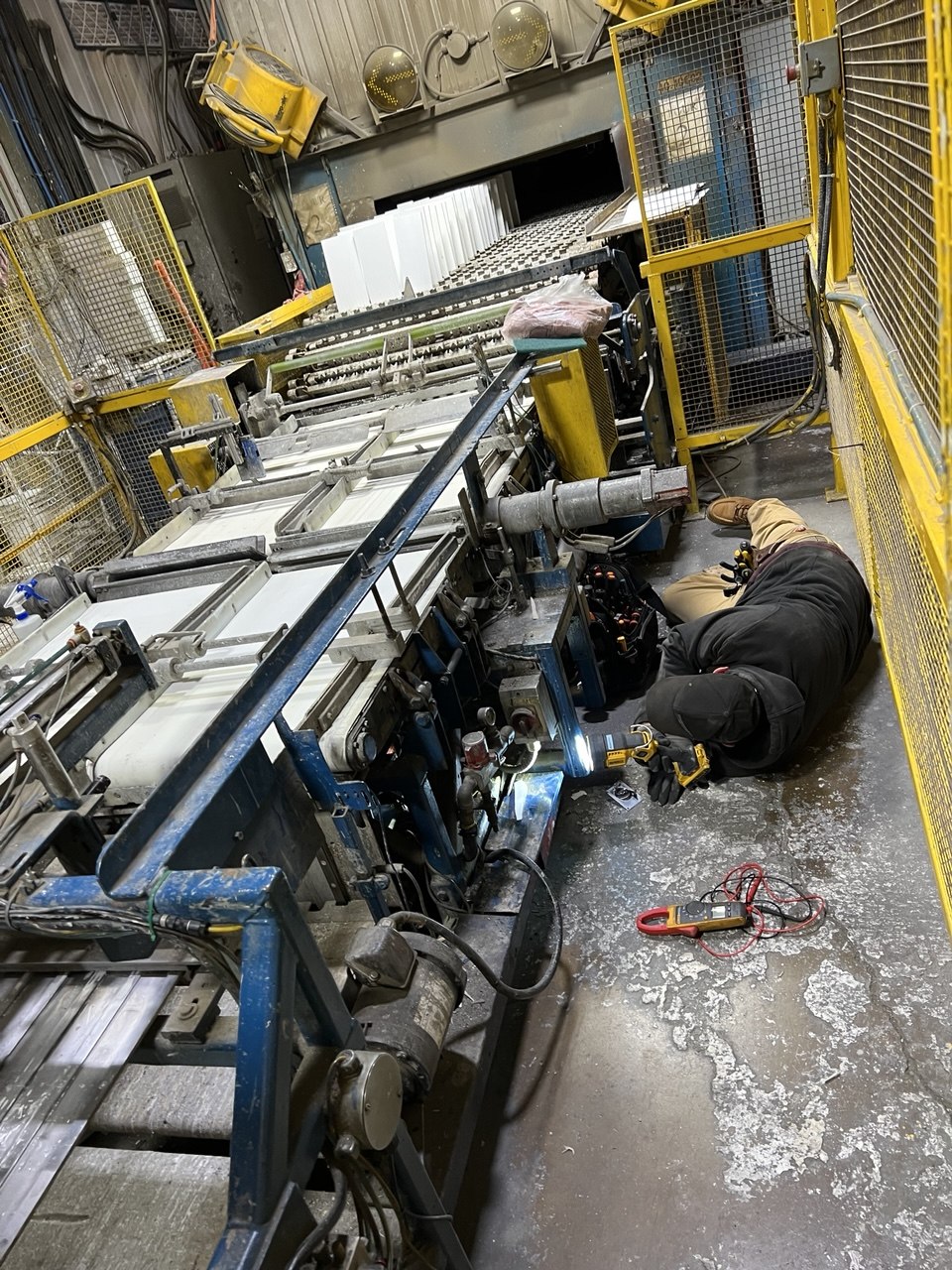 KEC technician diagnosing machine under the conveyor